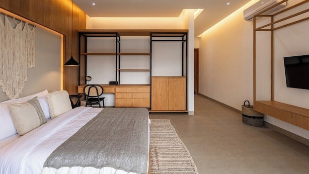 Un dormitorio moderno con cama, escritorio y televisor.