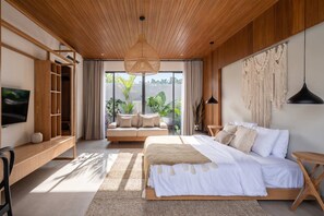 A modern bedroom with a large bed, a TV, and a view of greenery outside. - Brand New Opulent Villa, Huge Pool, Best Location (Badung Regency)
