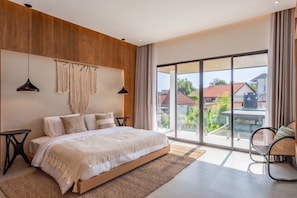 Ein modernes Schlafzimmer mit einem großen Bett, Holzvertäfelung, Wanddeko aus Makramee und Blick ins Freie.