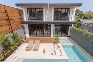 A modern two-story house with a swimming pool, outdoor seating, and a wooden fence. - Brand New Opulent Villa, Huge Pool, Best Location (Badung Regency)