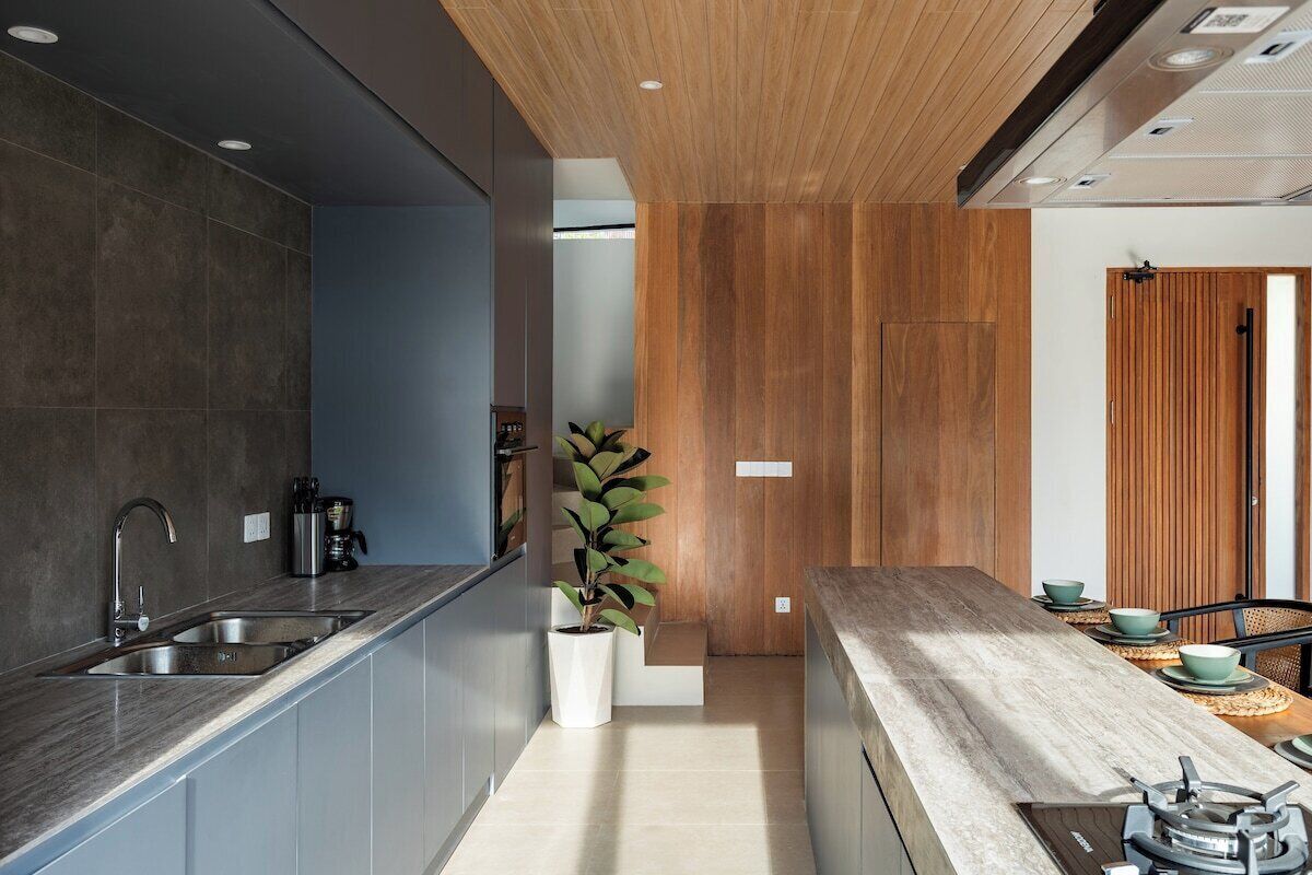 Une cuisine moderne dotée d’un évier encastré, d’éléments décoratifs en bois et d’un coin repas avec une table et des chaises.