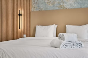 Ein Hotelzimmer mit einem Bett, weißen Leinentextilien, einer Wand aus Holzpaneelen und einem Lichtschalter.