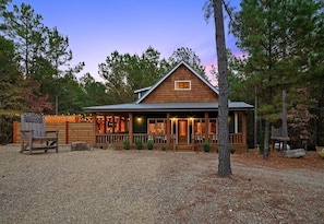 A lodge with a wooden exterior, a porch, and a sign indicating it is a cow-calf sale event. - NEW! Pool, Hot Tub, Pickleball, Rope Course, EV (Broken Bow)
