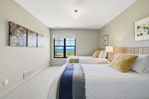 A bedroom with two beds, a large window, and artwork on the walls. - Welcome to The Sunset Lakehouse, a private waterfront retreat where modern farmhouse design meets the natural beauty of Prince Edward County. (Stinson Block Rd, Consecon, ON K0K 1T0, Canada)
