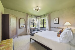A hotel room with a bed, a desk, a chair, a wardrobe, and a window with curtains. - Welcome to The Sunset Lakehouse, a private waterfront retreat where modern farmhouse design meets the natural beauty of Prince Edward County. (Stinson Block Rd, Consecon, ON K0K 1T0, Canada)