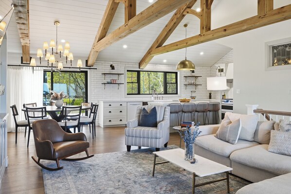 A spacious living area with a dining table, sofas, and a kitchen in the background. - Welcome to The Sunset Lakehouse, a private waterfront retreat where modern farmhouse design meets the natural beauty of Prince Edward County. (Stinson Block Rd, Consecon, ON K0K 1T0, Canada)