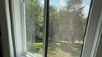 Une fenêtre donnant sur un espace verdoyant et des arbres.