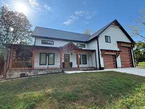 Une maison à deux étages avec un porche couvert, un garage et une pelouse bien entretenue.