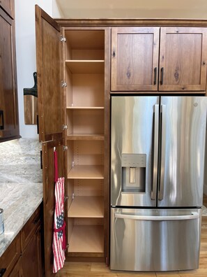 Une cuisine avec des meubles en bois, un réfrigérateur en acier inoxydable et un plan de travail en marbre.