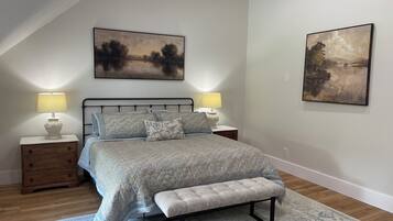 Une chambre à coucher comprenant un lit, deux tables de chevet, un banc et deux lampes fixées au mur.