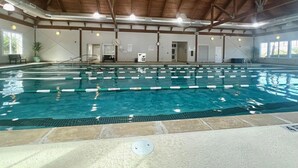 En inomhuspool med tydliga banor, ett träpanelat tak och en klocka på väggen.