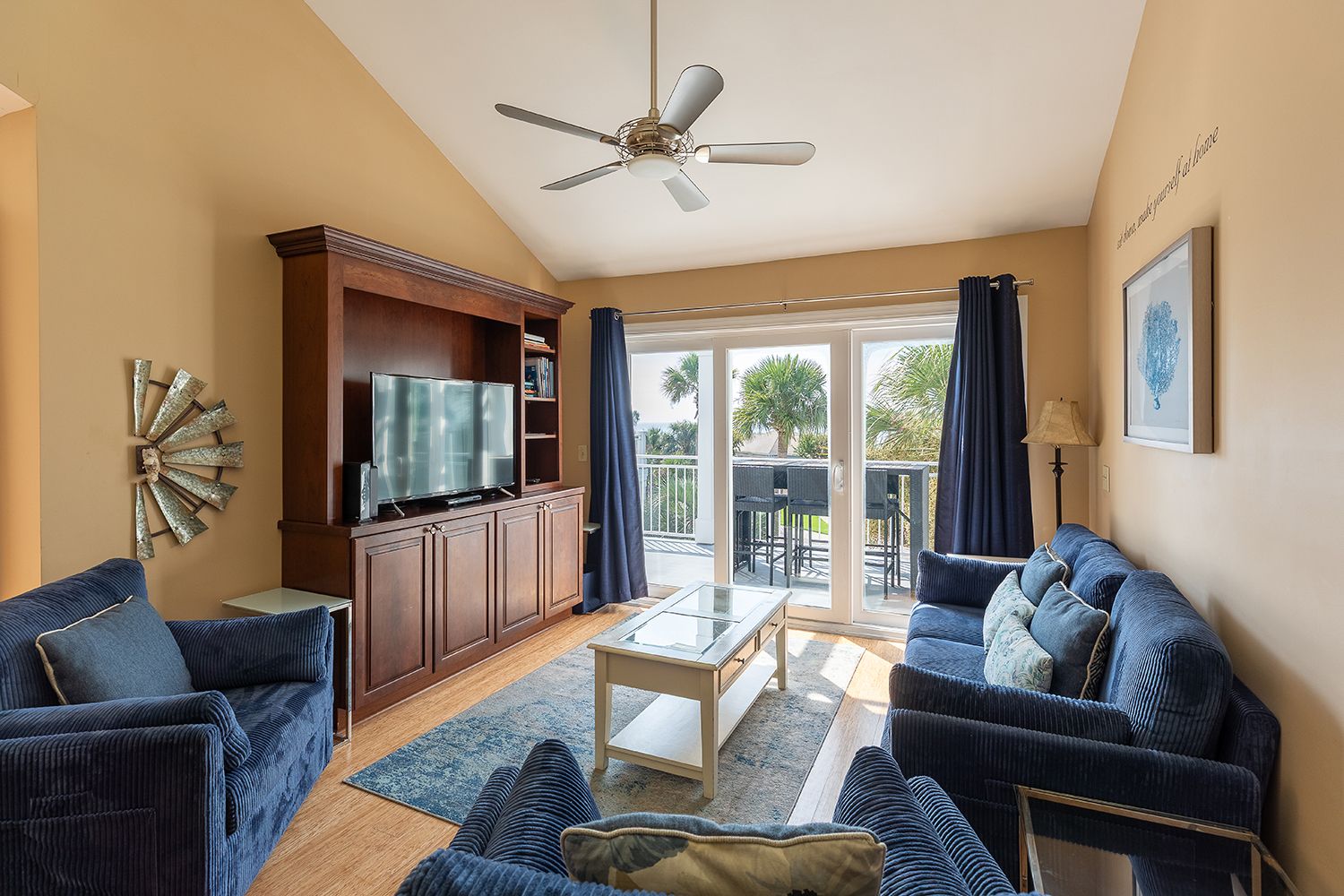 A living room with a television, wooden cabinet, two sofas, a coffee table, and a ceiling fan.