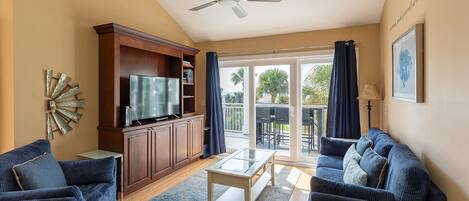 A living room with a television, wooden cabinet, two sofas, a coffee table, and a ceiling fan.