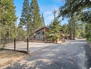 A cabin with a wooden exterior, a stone pathway leading to the entrance, and a metal gate. - Near BassLake, sleeps 16, BBQ, Game Room (Bass Lake)