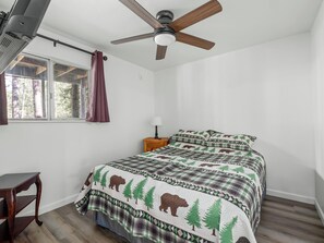 A bedroom with a bed, a ceiling fan, a window with curtains, a bedside table with a lamp, and a small wooden stool. - Near BassLake, sleeps 16, BBQ, Game Room (Bass Lake)