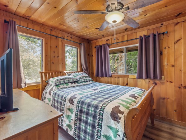 A wooden cabin room with a bed, a desk, and a ceiling fan. - Near BassLake, sleeps 16, BBQ, Game Room (Bass Lake)