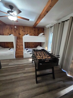 A room with bunk beds, a foosball table, wooden walls, and a ceiling fan. - Near BassLake, sleeps 16, BBQ, Game Room (Bass Lake)
