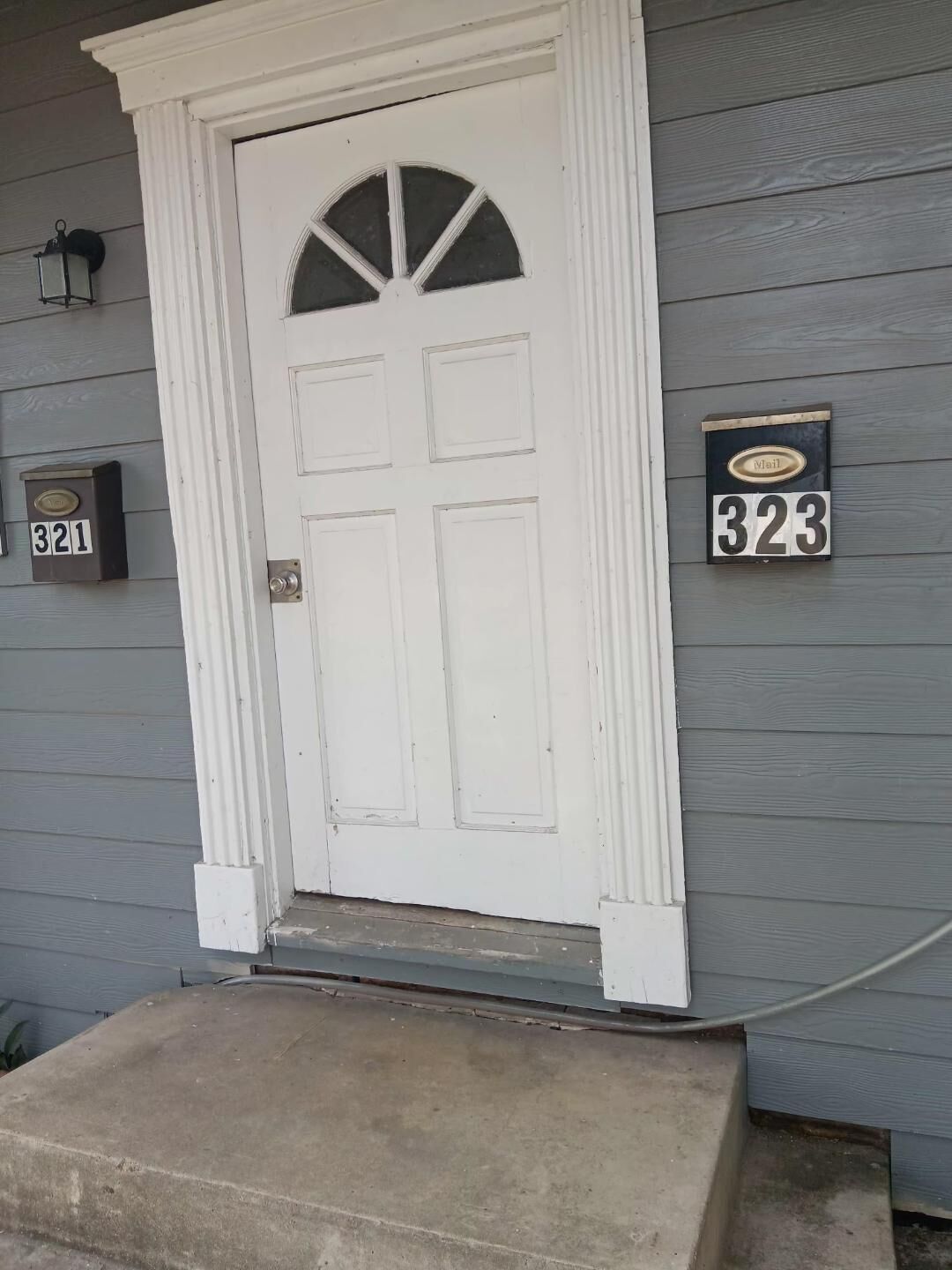 A white front door with a semi-circular window, a mailbox with the number 323, and a mailbox with the number 321.