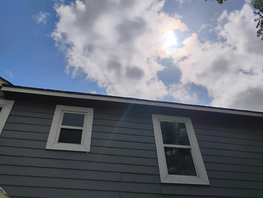 A building with two windows and a clear sky with clouds.