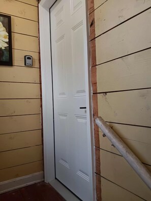 A white door with a metal handle, a small mailbox, and a wooden handrail.