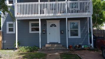 A two-story house with a front porch, a small front yard, and a driveway.