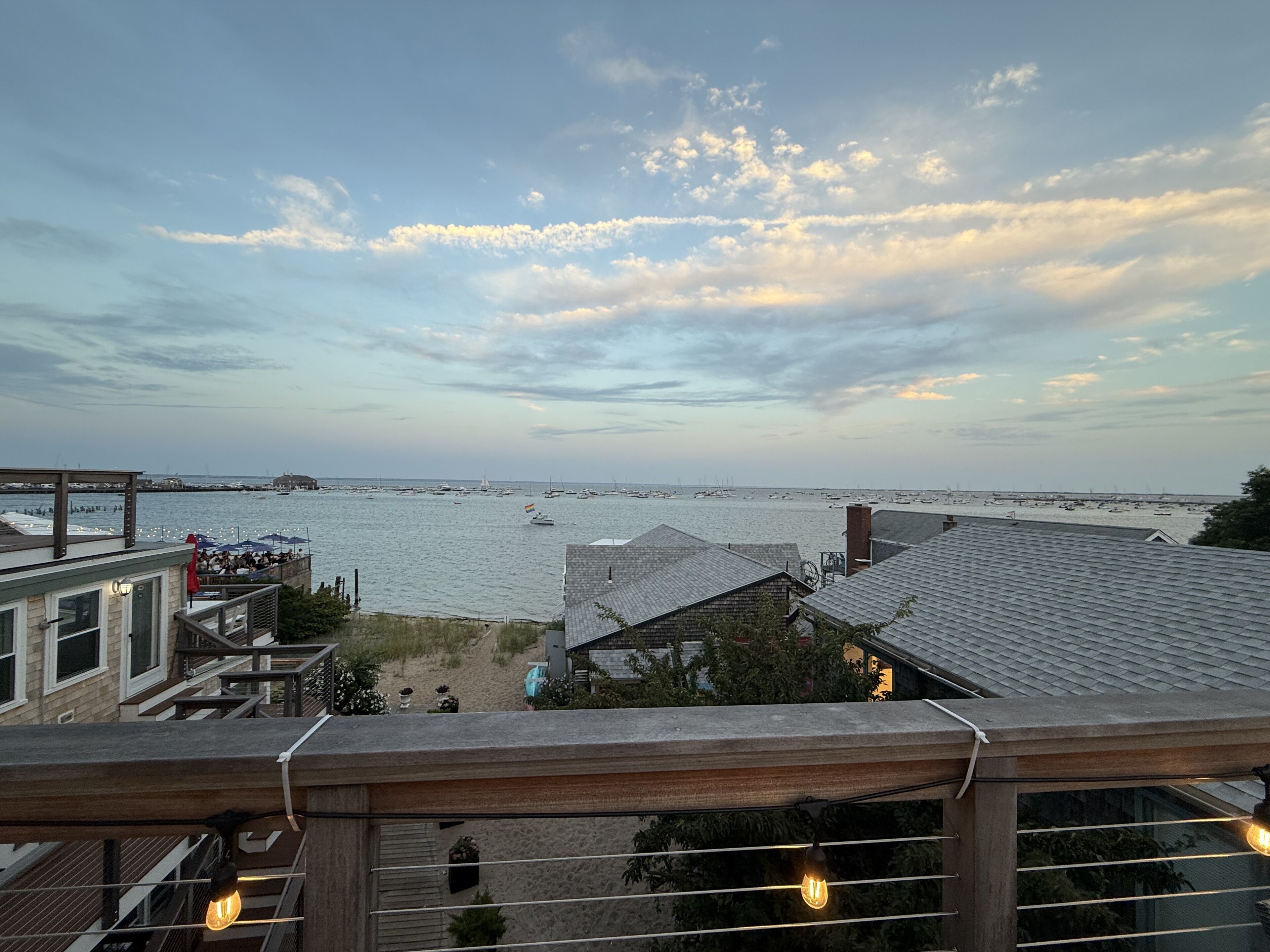 A coastal view from a balcony overlooking a marina with boats, a sandy beach, and a clear sky.