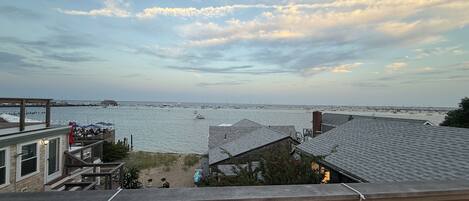 A coastal view from a balcony overlooking a marina with boats, a sandy beach, and a clear sky.