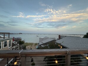 A coastal view from a balcony overlooking a marina with boats, a sandy beach, and a clear sky.