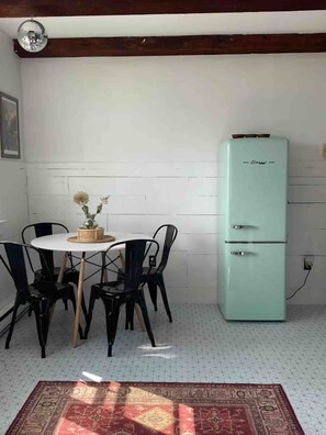 A dining area with a table and chairs, a vintage-style refrigerator, and a patterned rug on the floor. - Beachfront 2BR Penthouse Deck + Bay Views (Provincetown)