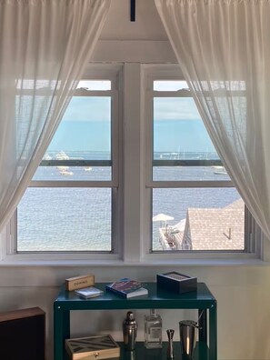 A room with a view of the sea through a window with white curtains. - Beachfront 2BR Penthouse Deck + Bay Views (Provincetown)