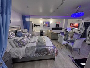 Une chambre moderne avec un grand lit, un bureau, un canapé et un téléviseur.