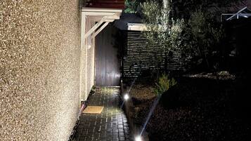 A pathway leading to a building with a textured wall and a wooden deck.