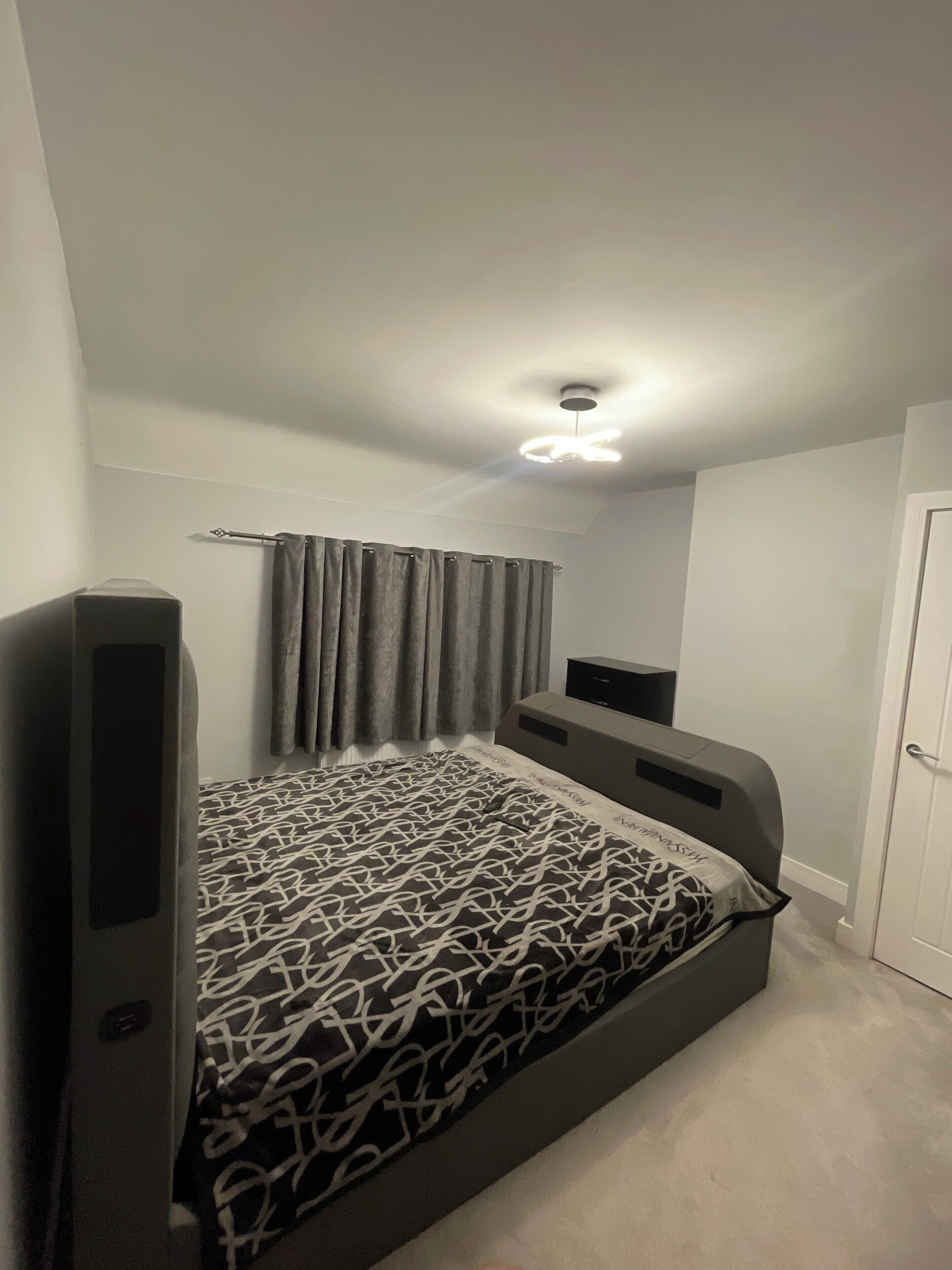 A bedroom with a bed, a television, and a ceiling fan.