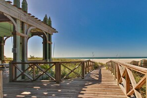 Ein hölzerner Steg führt zu einem Strand, links davon befindet sich ein Gazebo.
