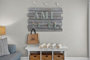 Ein an der Wand befestigtes Holzschild mit den Buchstaben 'AMT' und eine braune Tragetasche, die an einem Haken hängt.