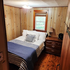 Ein Schlafzimmer mit Bett, Schminktisch, Fenster und Lampe.