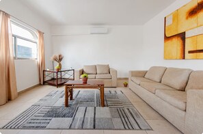 A modern living room with a sofa, coffee table, and a large abstract painting. - El Sol: apartment with rooftop lounge access minutes from 5 Avenida (Playa del Carmen)