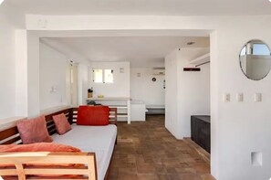 A modern, well-lit room with a wooden bench, a white sofa, and a dining area with a white table and chairs. - El Sol: apartment with rooftop lounge access minutes from 5 Avenida (Playa del Carmen)