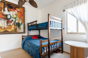 A bunk bed room with a painting on the wall, a window with curtains, and a small round table. - El Sol: apartment with rooftop lounge access minutes from 5 Avenida (Playa del Carmen)