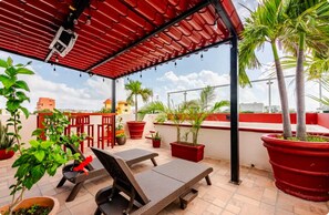 A rooftop terrace with red chairs, potted plants, and a red pergola. - El Sol: apartment with rooftop lounge access minutes from 5 Avenida (Playa del Carmen)