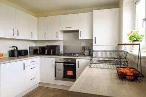 A kitchen with white cabinets, a gas stove, a microwave, and a fruit basket.