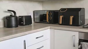A kitchen with a kettle, toaster, and air fryer on the countertop. - 3-Bed House, Sleeps 7 with Parking & Garden (Wishaw)