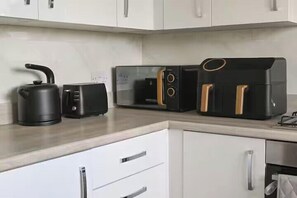Een keuken met een waterkoker, broodrooster en heteluchtfriteuse op het aanrecht.