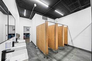 A modern restroom with a mirror, sinks, and a wooden partition. - Paradise Pods (Surfers Paradise)