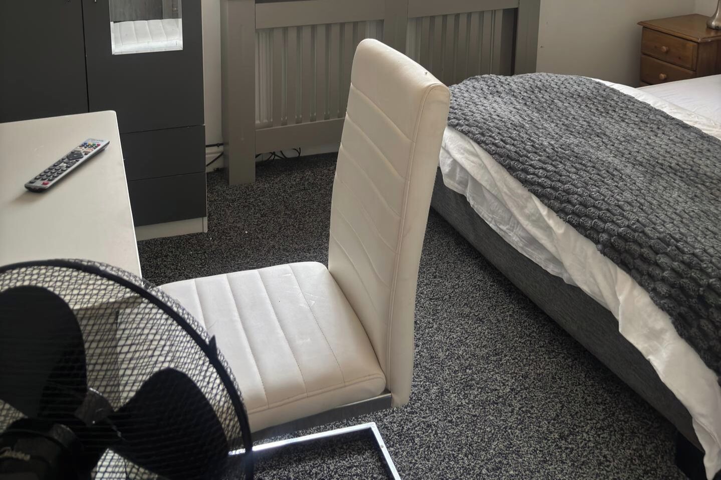 Ein Hotelzimmer mit einem Bett, einem Sessel, einem Schreibtisch und einer Fernbedienung.