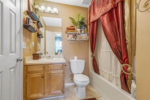 Ein Badezimmer mit Toilette, Waschbecken, Holzschränken und einer Duschvorhang.