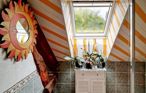 Ein Badezimmer mit Oberlicht, Streifenmuster an den Wänden, einem dekorativen Spiegel und einem Fliesenboden.