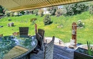 An outdoor dining area with wicker chairs and a glass table, surrounded by a well-maintained lawn and garden. - Maison avec piscine et jaccuzz (Saint-Jal)