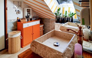 A kitchen with a tiled backsplash, a wooden cabinet, a trash bin, and a sink with a stone basin. - Maison avec piscine et jaccuzz (Saint-Jal)