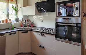 A modern kitchen with a gas stove, a Bosch oven, and a flat-screen TV mounted above the stove. - Maison avec piscine et jaccuzz (Saint-Jal)